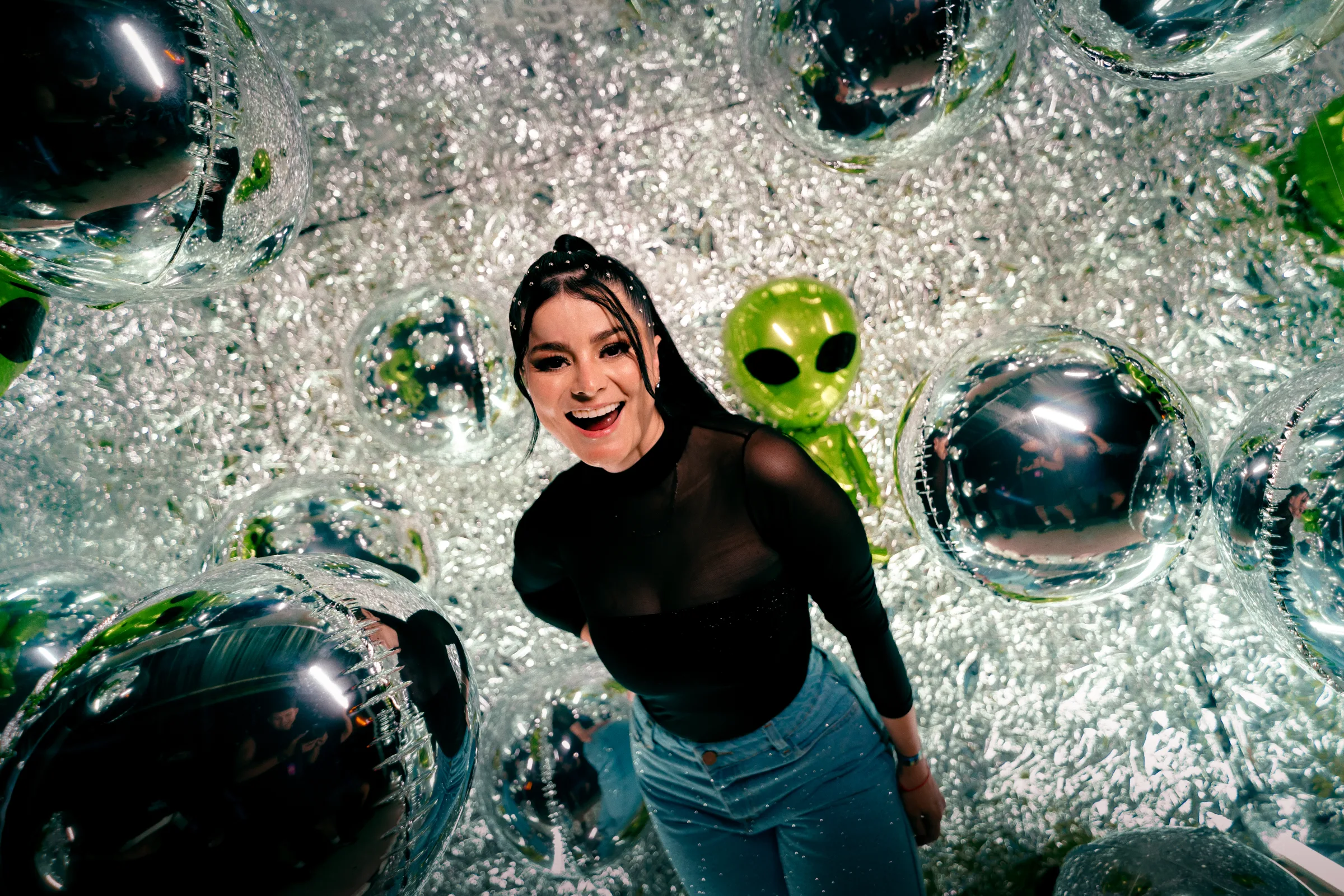 Asistente sonriendo junto a globos plateados en una instalación del festival