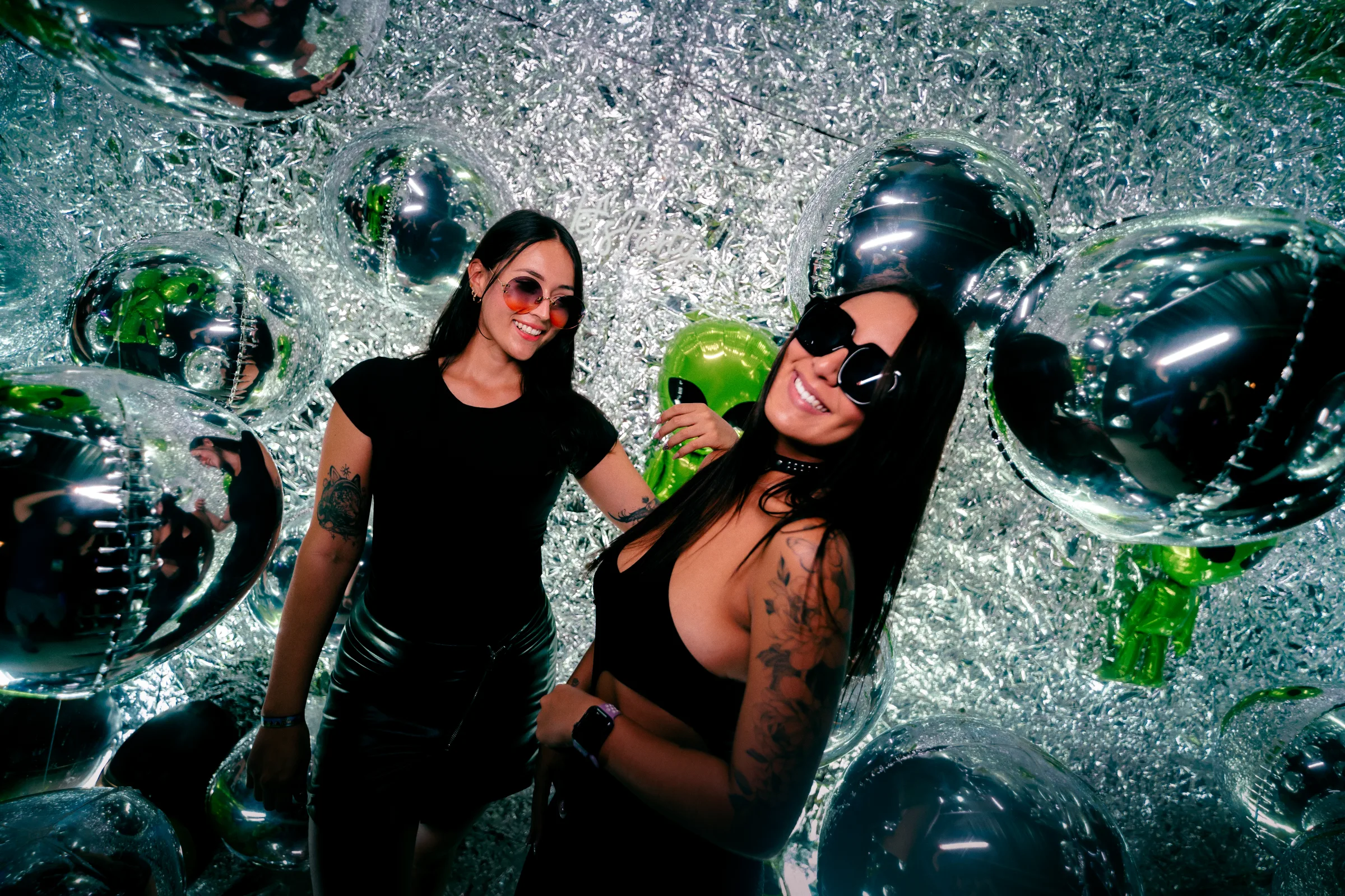 Dos amigas frente a una instalación de reflejos plateados