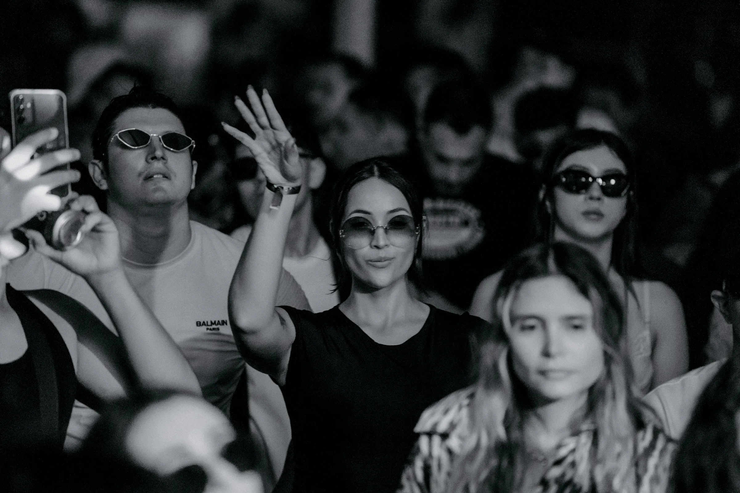 Público en blanco y negro con una asistente levantando la mano