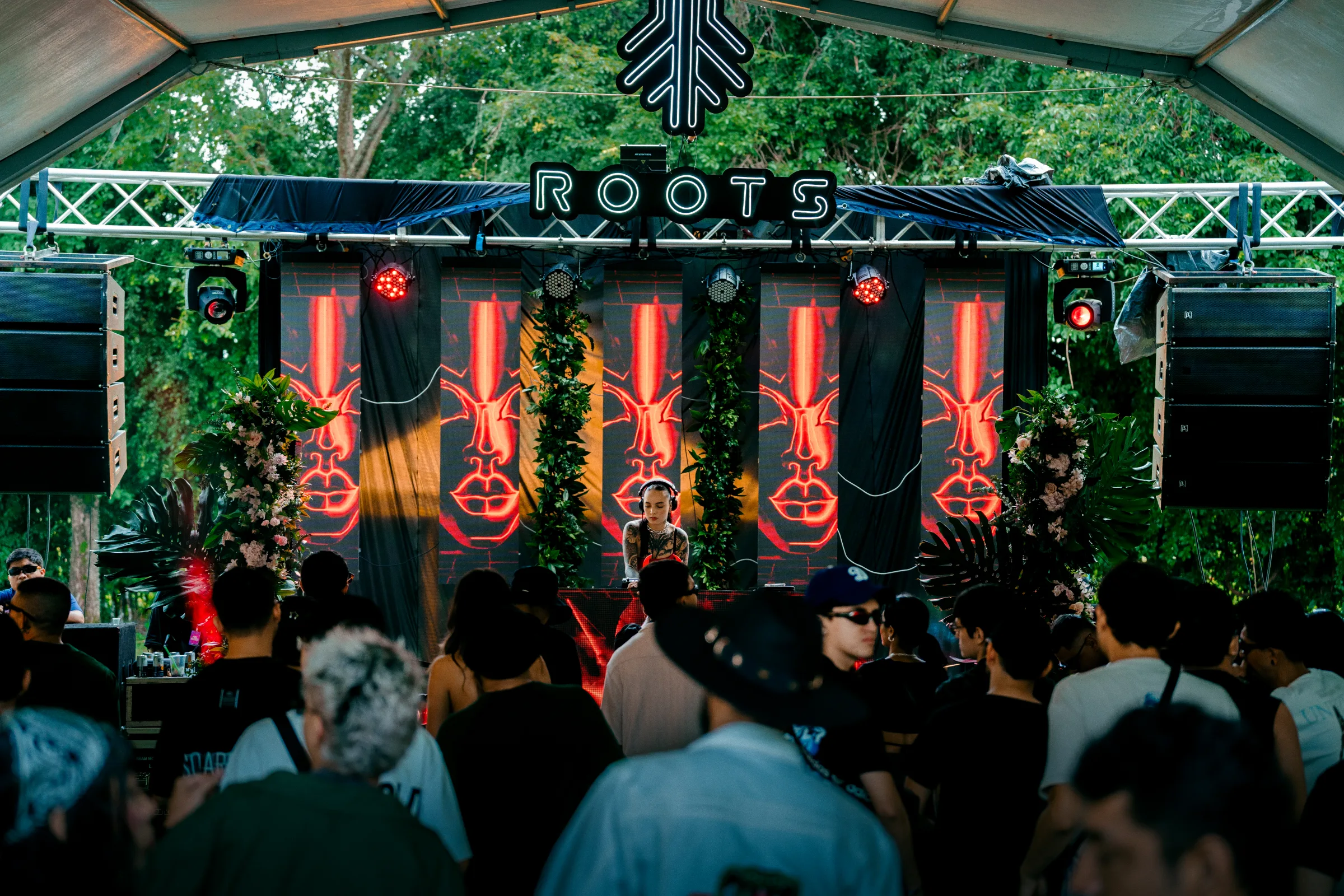 Escenario ROOTS con luces rojas y público frente a la cabina